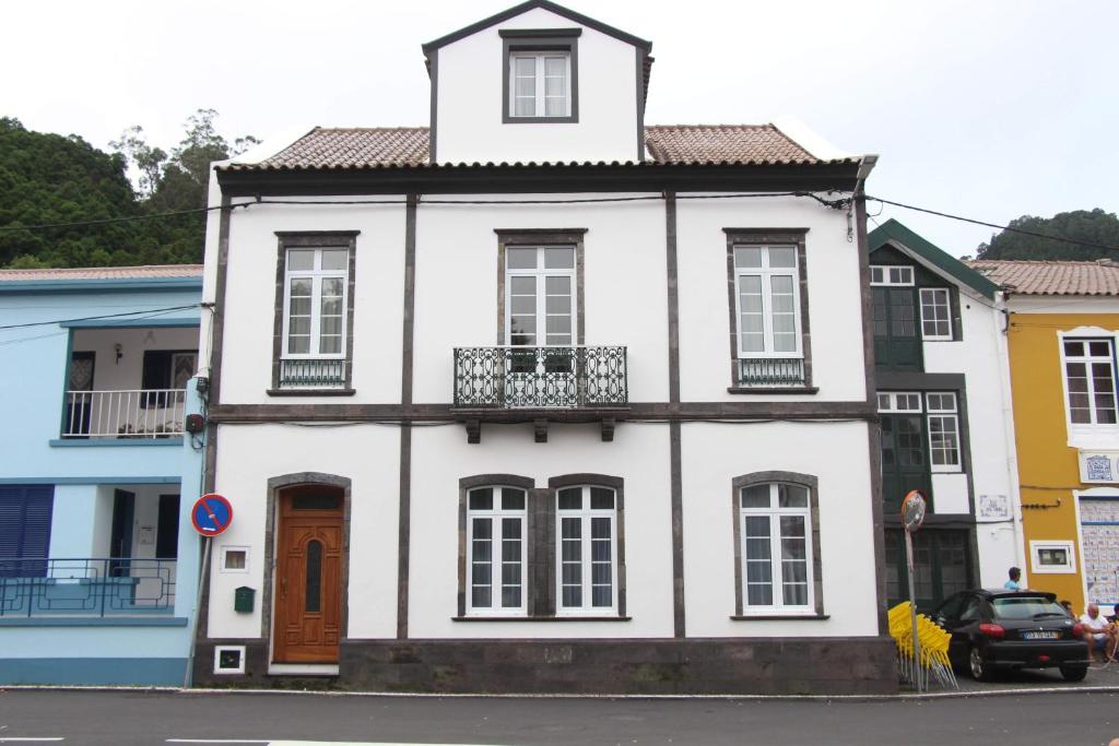 een wit huis met een balkon in een straat bij Casa Galante in Furnas