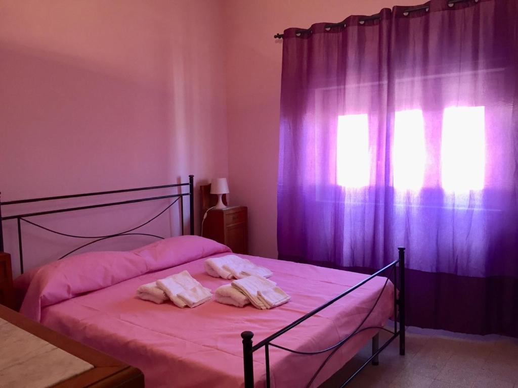 1 dormitorio con cama con sábanas rosas y ventana en My lovely Home, en Noto