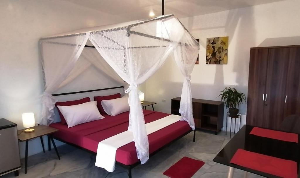 a bedroom with a red and white bed with a canopy at Lonos Circle Private Garden in Romblon