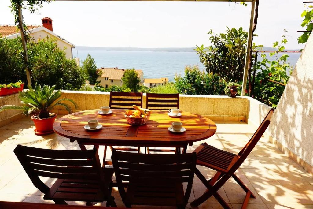 - une table et des chaises en bois sur une terrasse donnant sur l'océan dans l'établissement Apartments Ana - sea view;, à Zavala
