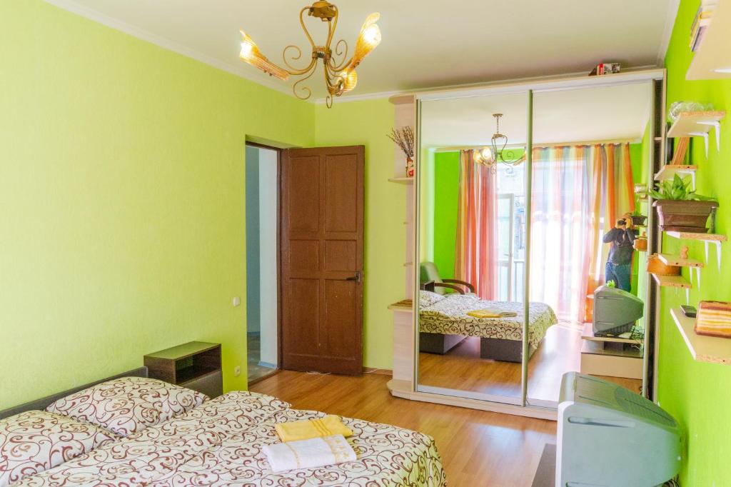 - une chambre avec des murs verts, un lit et un miroir dans l'établissement Квартира по улице Цитадельная 4, à Kiev