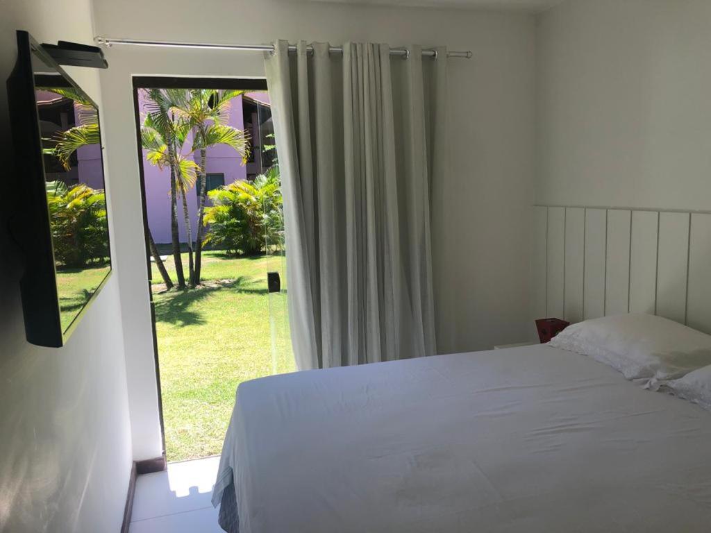 1 dormitorio con 1 cama y puerta corredera de cristal en Itacimirim - Quinta das Lagoas Residence, en Itacimirim
