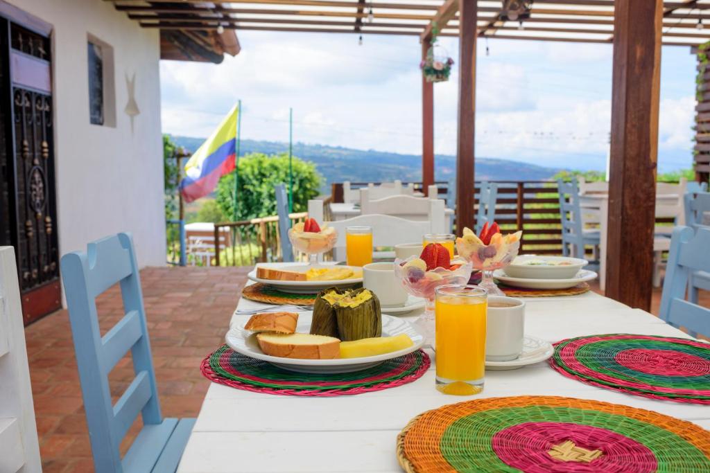 a table with a breakfast of orange juice and bread at Hotel Campestre El Santuario in Barichara