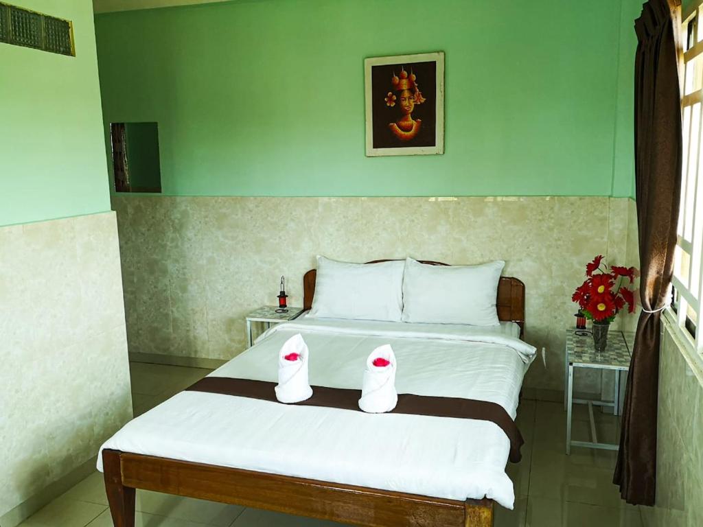 ein Schlafzimmer mit einem Bett mit zwei weißen Schuhen darauf in der Unterkunft Route 76 Guest House in Sen Monorom