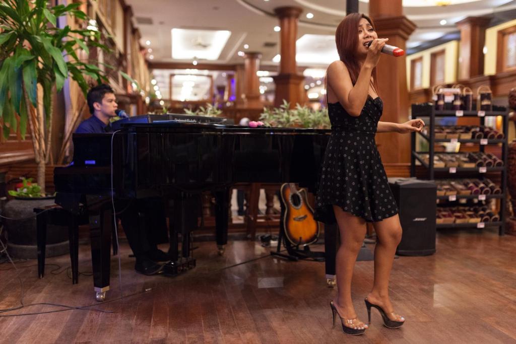 a woman singing into a microphone in front of a piano at Prince Angkor Hotel & Spa in Siem Reap