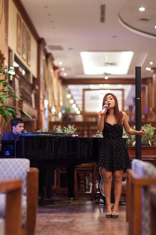 a woman singing into a microphone in front of a piano at Prince Angkor Hotel & Spa in Siem Reap