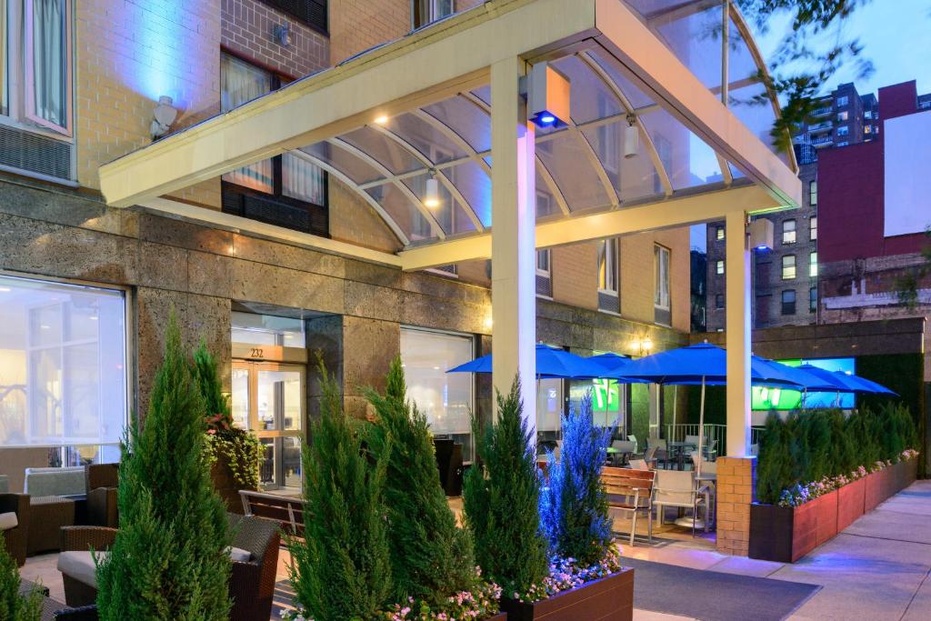 a restaurant with tables and blue umbrellas in front of a building at Holiday Inn Express New York City Chelsea, an IHG Hotel in New York