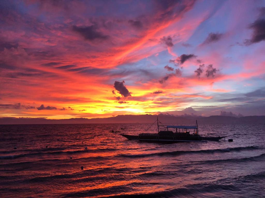 a boat in the ocean with a sunset at Marina Village in Moalboal
