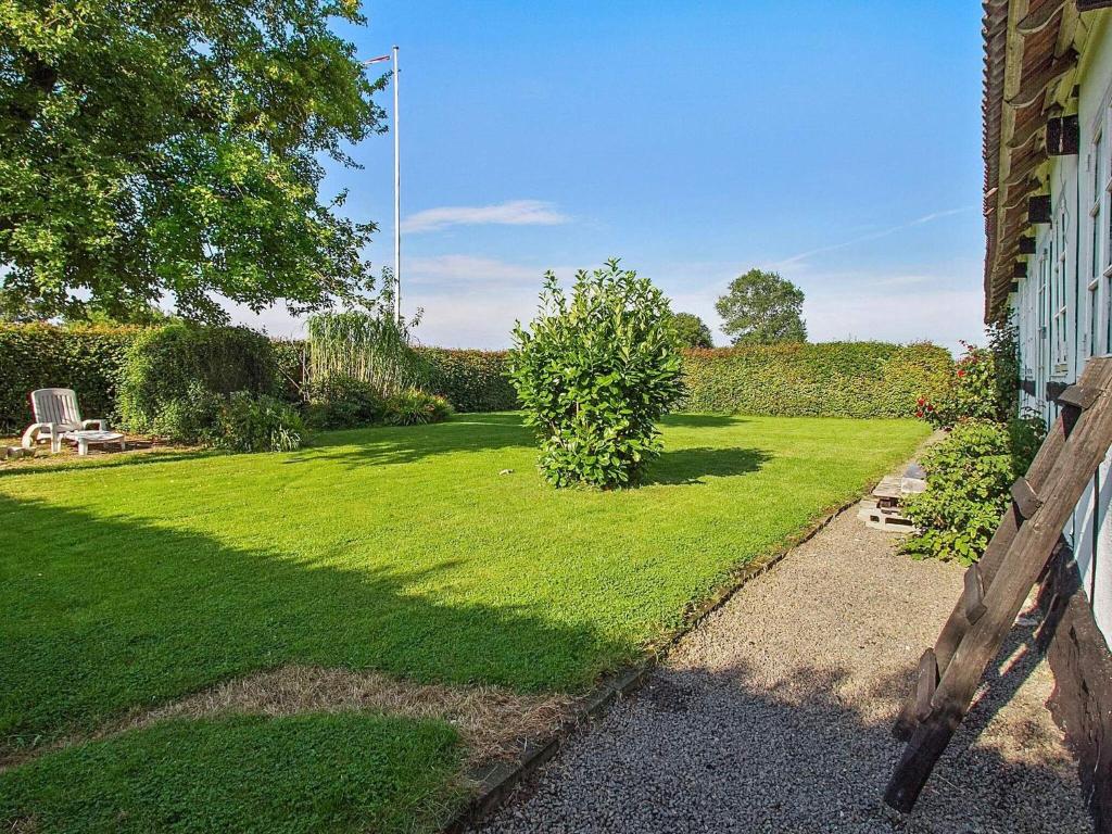 einen Garten mit einer Liegewiese mit einem Stuhl und einem Zaun in der Unterkunft Holiday home Aakirkeby IX in Åkirkeby