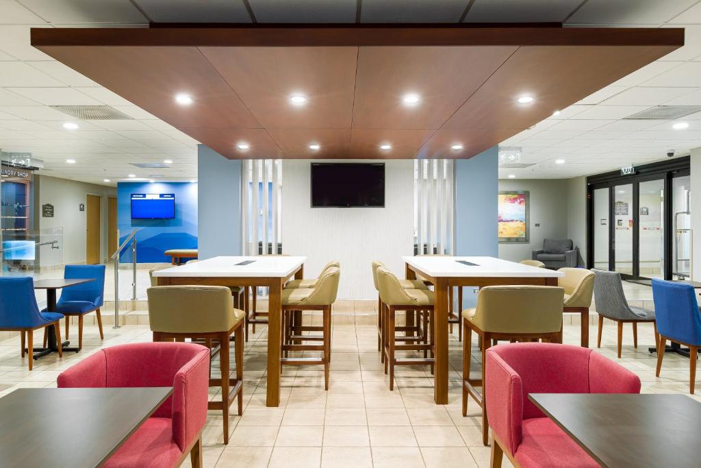 a dining room with tables and chairs and a flat screen tv at Holiday Inn Express San Jose Costa Rica Airport by IHG in Alajuela City