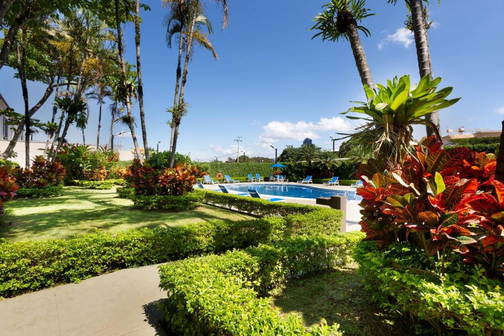 a resort yard with a swimming pool and palm trees at Holiday Inn Express San Jose Costa Rica Airport by IHG in Alajuela City