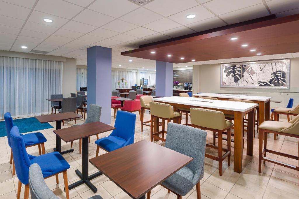 a dining room with tables and chairs and a cafeteria at Holiday Inn Express San Jose Costa Rica Airport by IHG in Alajuela City