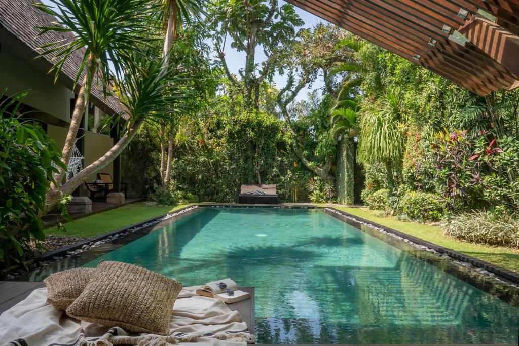 a swimming pool in the middle of a yard with trees at Ametis Villa -Adult Only in Canggu