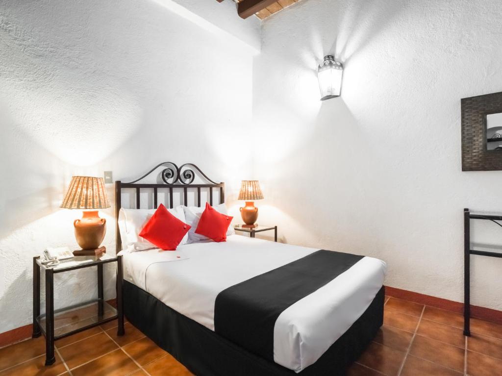 1 dormitorio con 1 cama grande con almohadas rojas en Capital O El Nito, en Oaxaca City