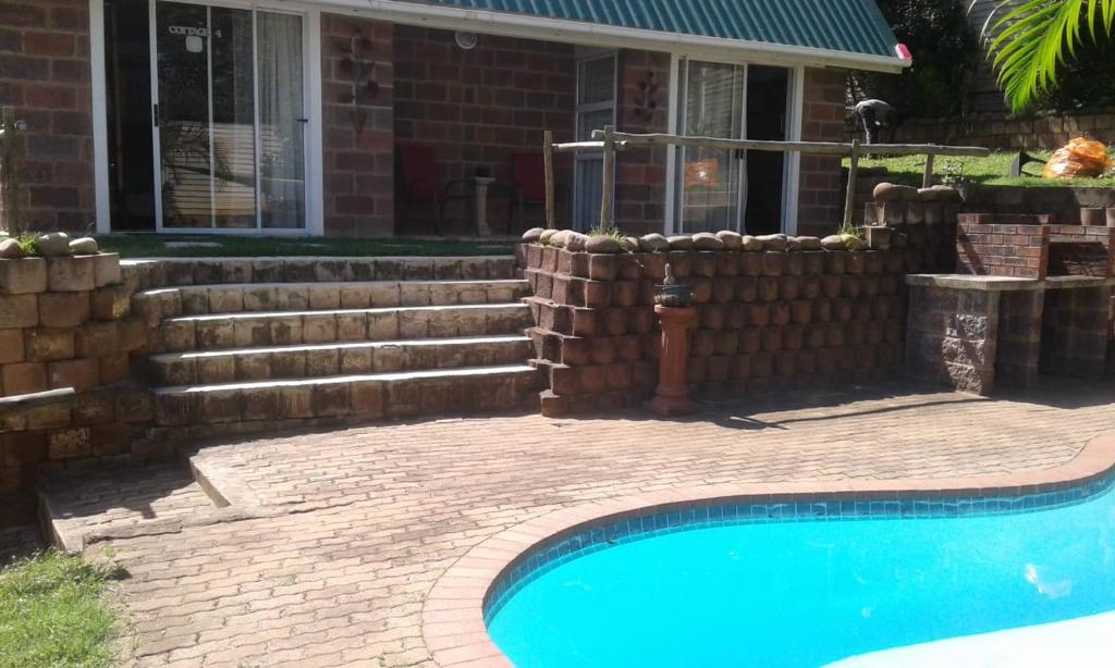 a brick fence and a swimming pool in front of a house at Lothian rd Cottage in Durban