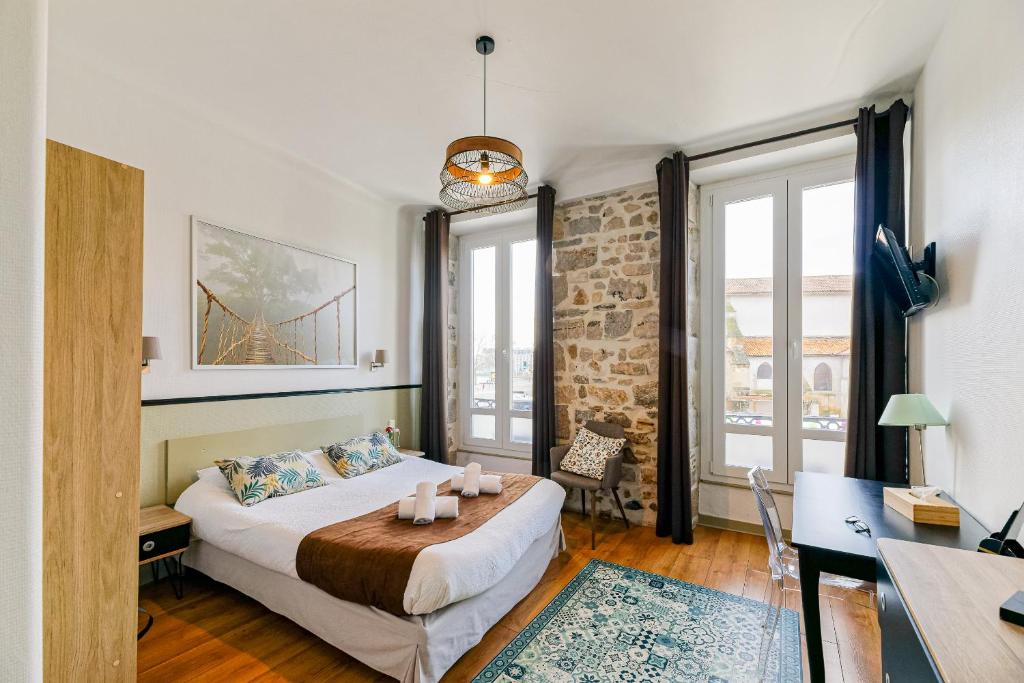 a bedroom with a bed and a desk and windows at Hotel Cote Basque in Bayonne