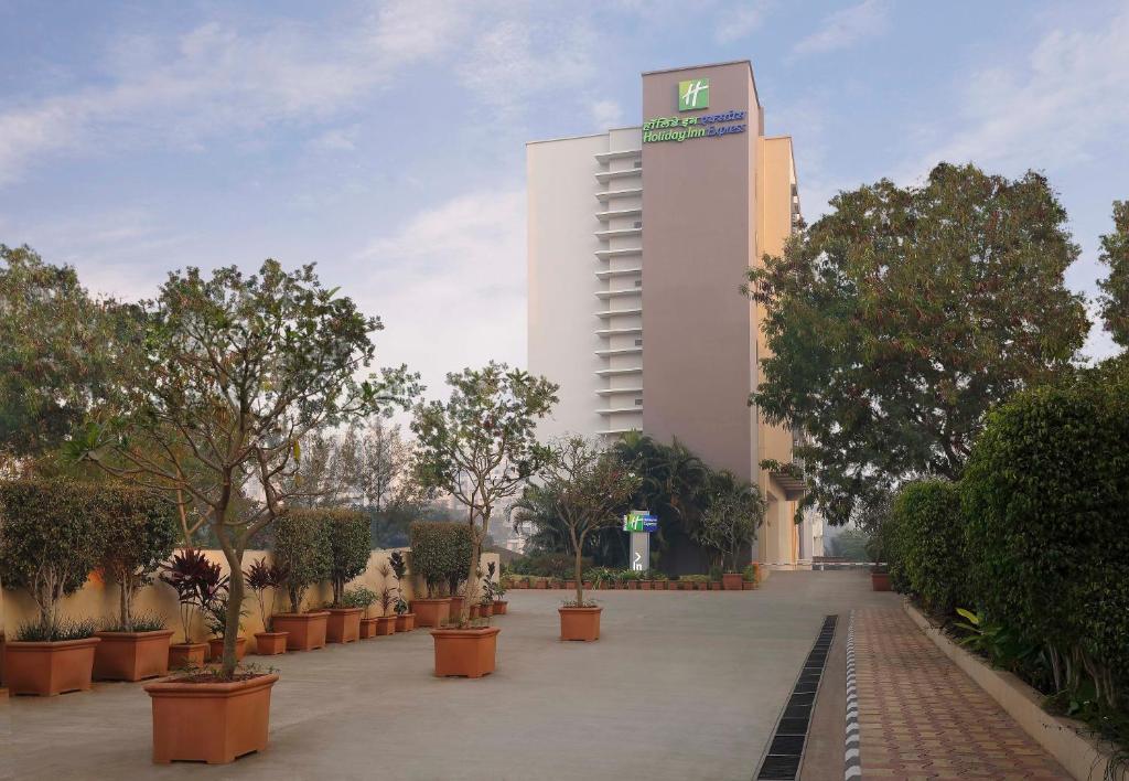 un edificio alto y blanco con árboles delante en Holiday Inn Express Pune Hinjewadi, an IHG Hotel, en Pune
