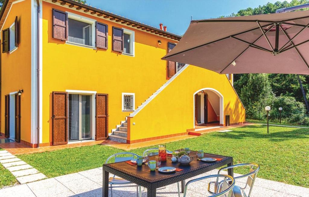 einen Tisch mit einem Regenschirm vor einem Haus in der Unterkunft Holiday Pianamaggio in Carrara