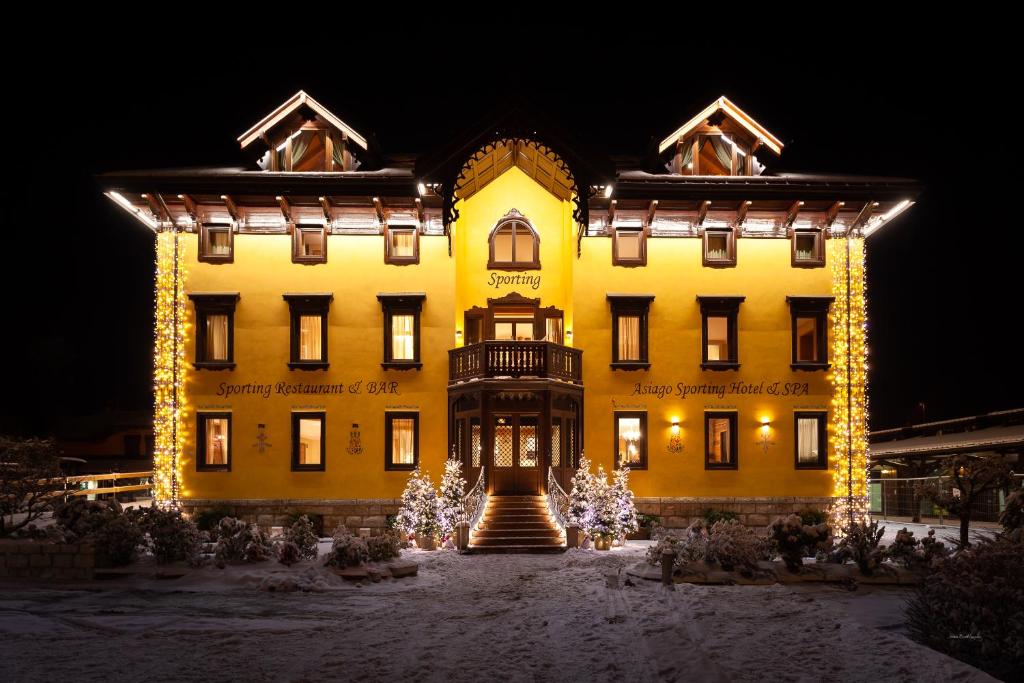 um grande edifício amarelo com luzes de Natal em frente em Asiago Sporting Hotel & Spa em Asiago