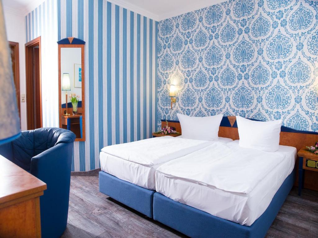 ein blau-weißes Schlafzimmer mit einem Bett und einem Stuhl in der Unterkunft Pension Weinberg Güstrow in Güstrow