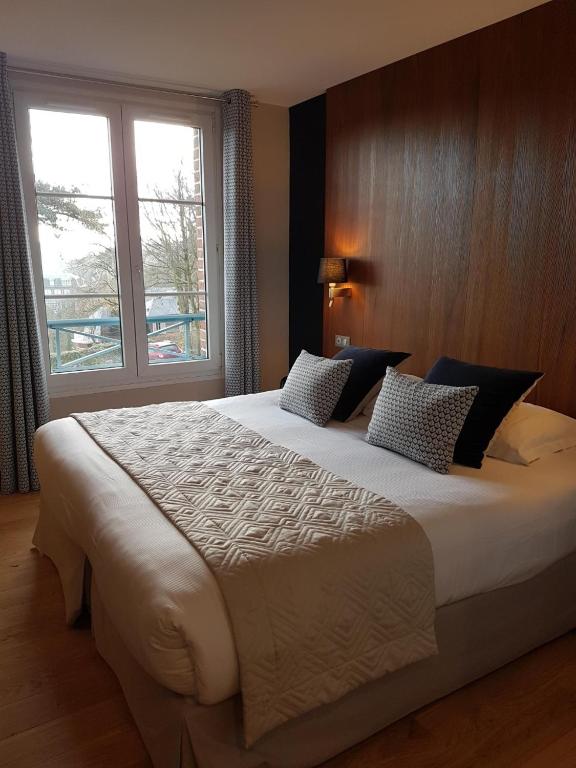 a large bed in a room with a large window at Dormy House in Étretat