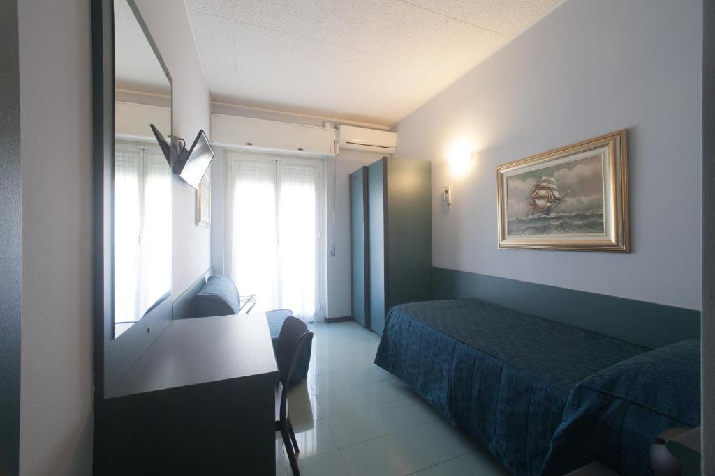 a bedroom with a bed and a desk and a window at Hotel Tirreno in Genoa