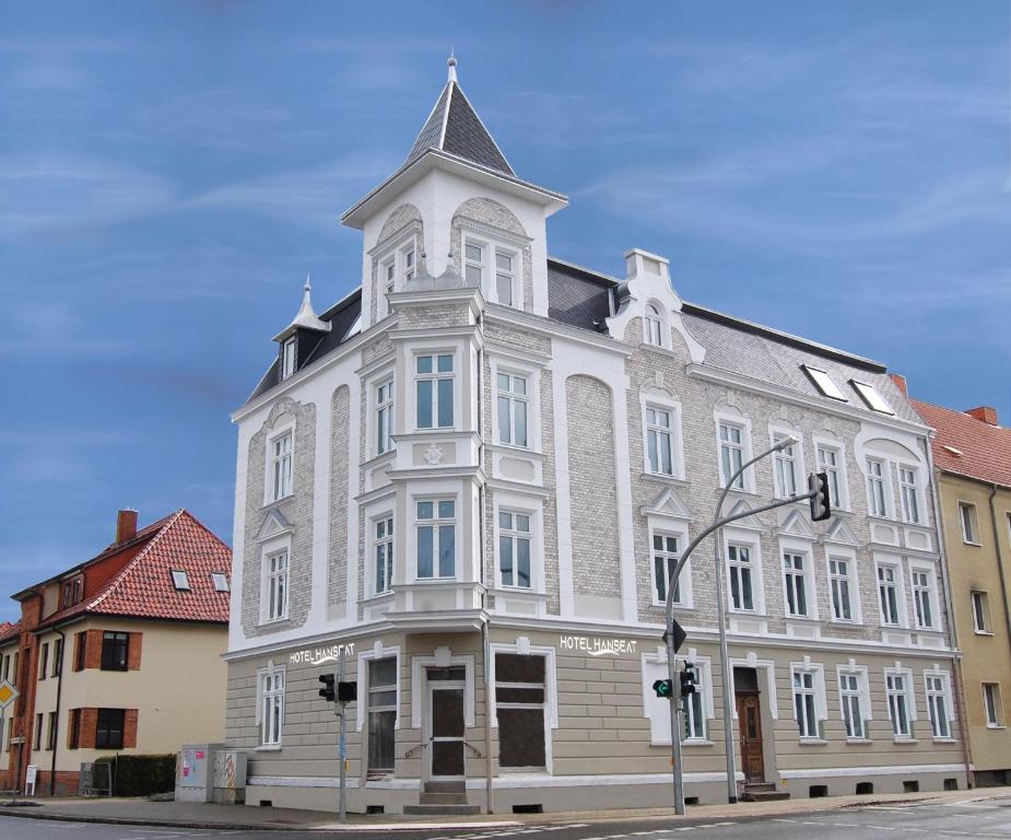 a large white building with a tower on a street at Hotel Hanseat Stralsund in Stralsund