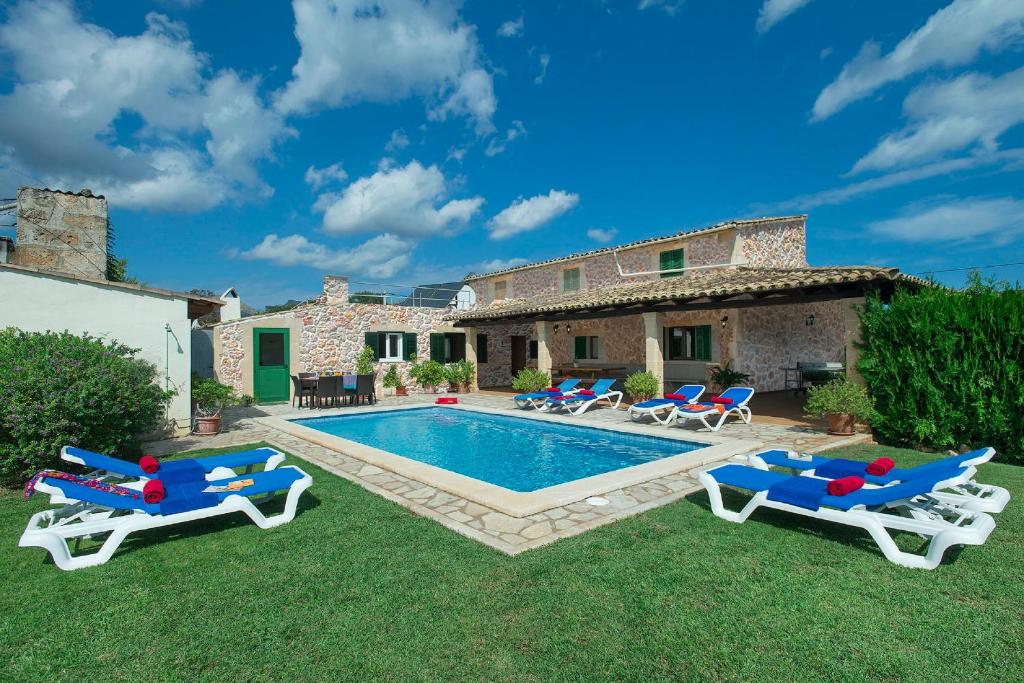a backyard with a swimming pool with chairs and a house at Owl Booking Villa Maria - Family and Friends in El Port
