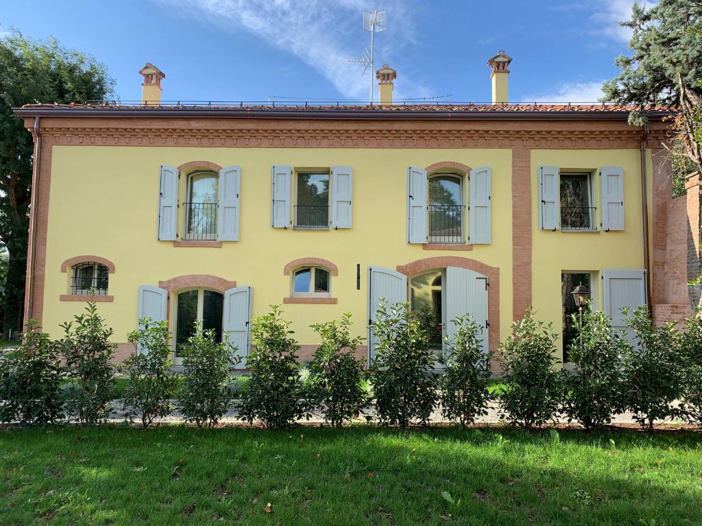 una casa gialla con finestre e un cortile di Antico Podere San Luca a Bologna