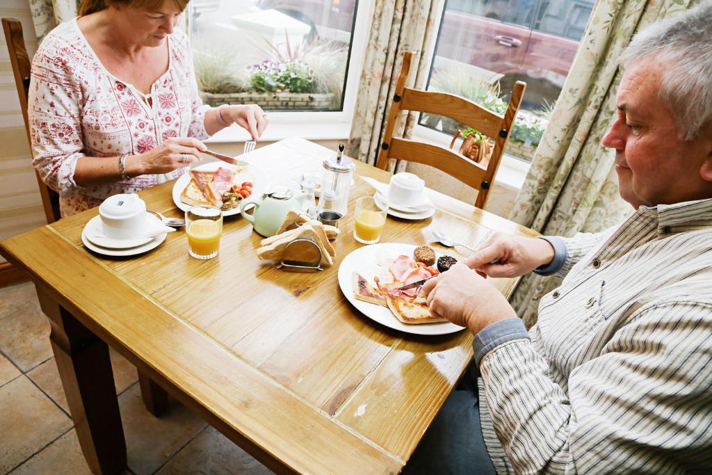 a man and woman sitting at a table eating food at Avarest House BB Adults Only in Portrush