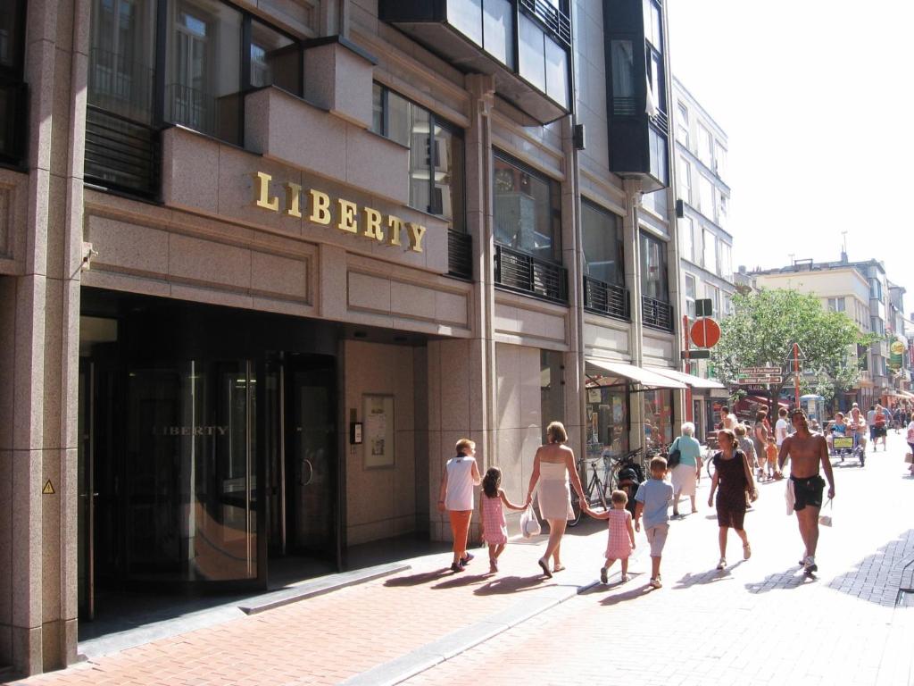 un groupe de personnes marchant dans une rue en face d'une bibliothèque dans l'établissement Liberty, à Blankenberge