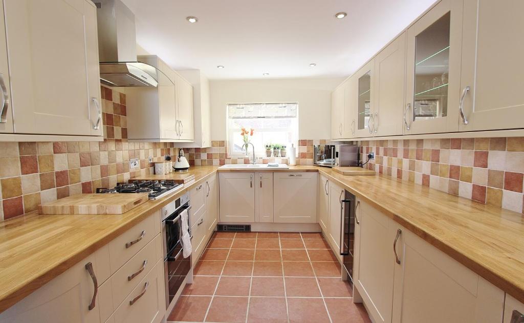 a kitchen with white cabinets and a tile floor at Goose's Getaway in Wells next the Sea