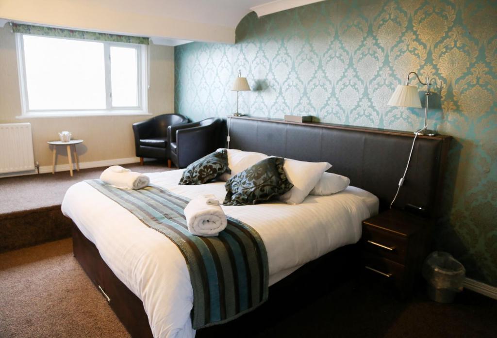 a bedroom with a large bed with a chair and a window at Avarest House BB Adults Only in Portrush