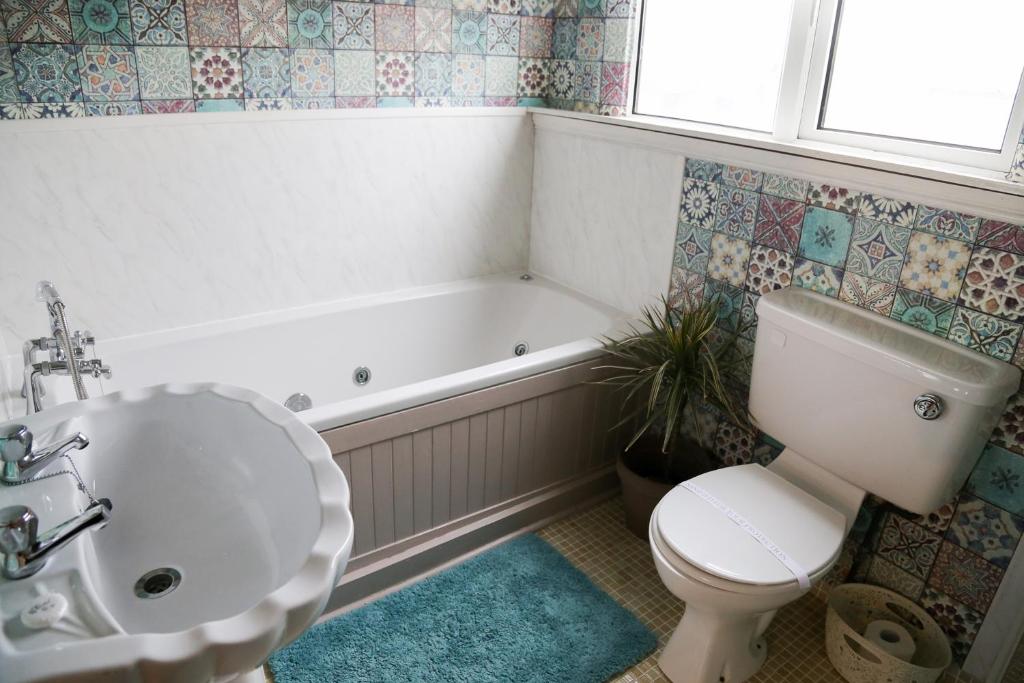 a bathroom with a toilet and a tub and a sink at Avarest House BB Adults Only in Portrush