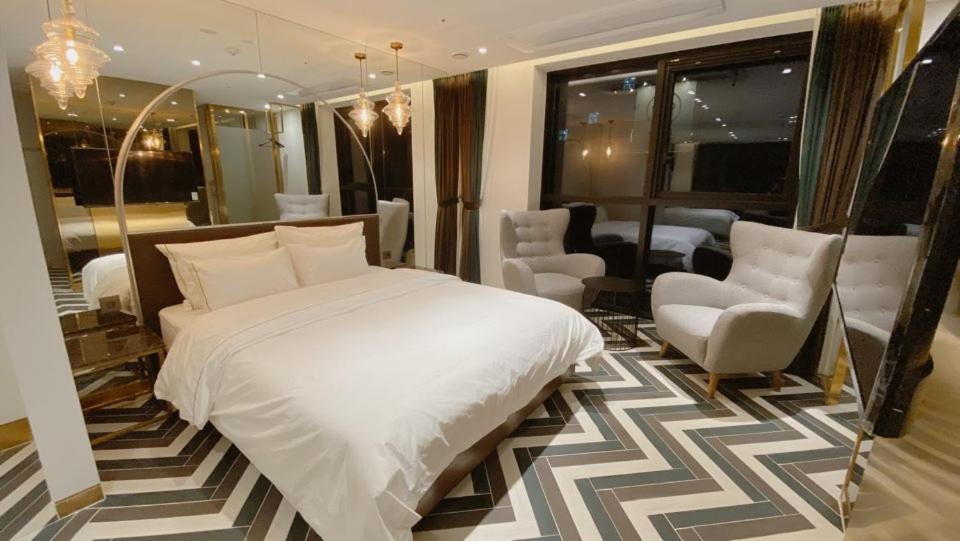 - une chambre avec un grand lit blanc et des chaises dans l'établissement Hotel the Castle Banyi, à Séoul