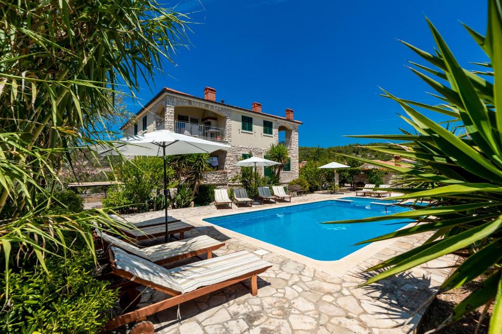 a villa with a swimming pool and a house at Komun Apartments in Vela Luka