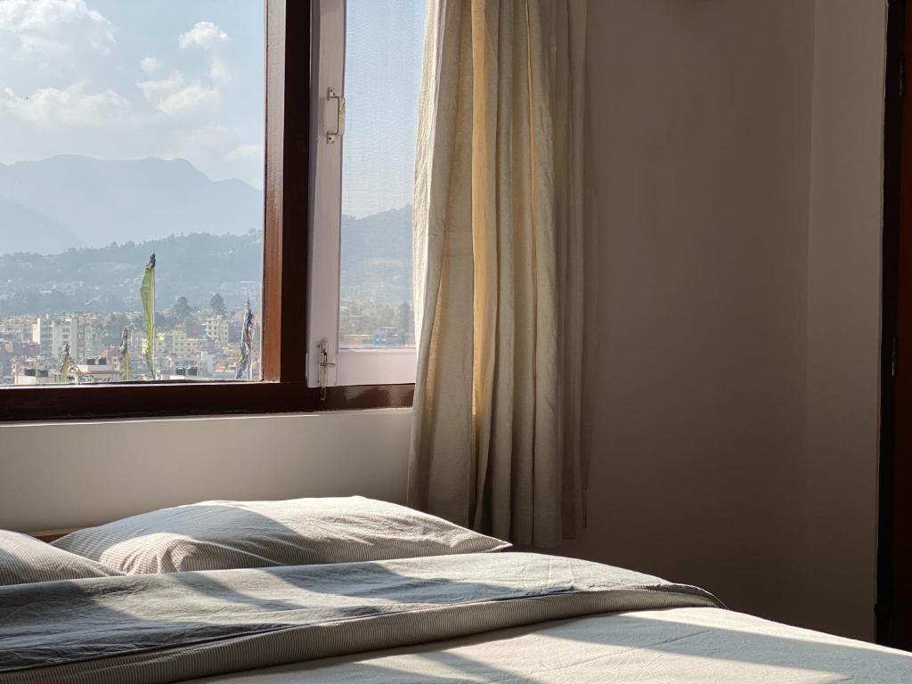 una camera da letto con un letto e una finestra con vista di Swayambhu View Guest House a Kathmandu