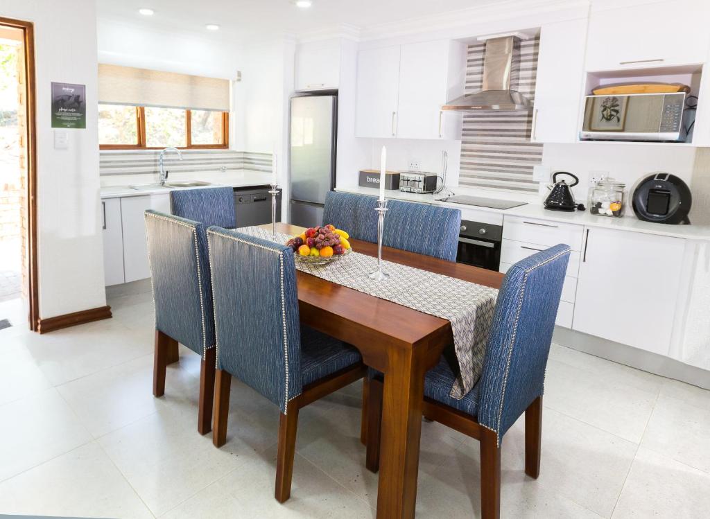 a kitchen with a wooden table and blue chairs at Kruger Park Lodge Unit No. 608B in Hazyview