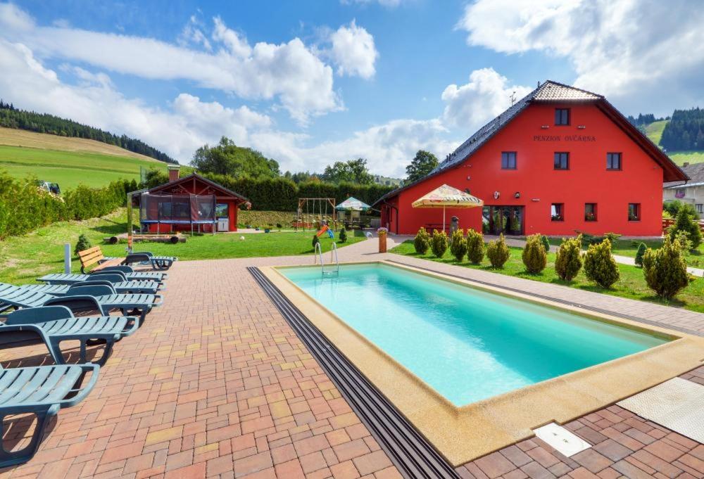 a red barn and a swimming pool in front of a red house at Penzion Ovčárna in Červená Voda