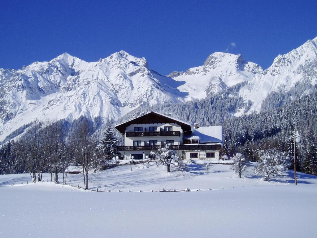 a house in the snow in front of a mountain at Sonnenhügel in Ramsau am Dachstein