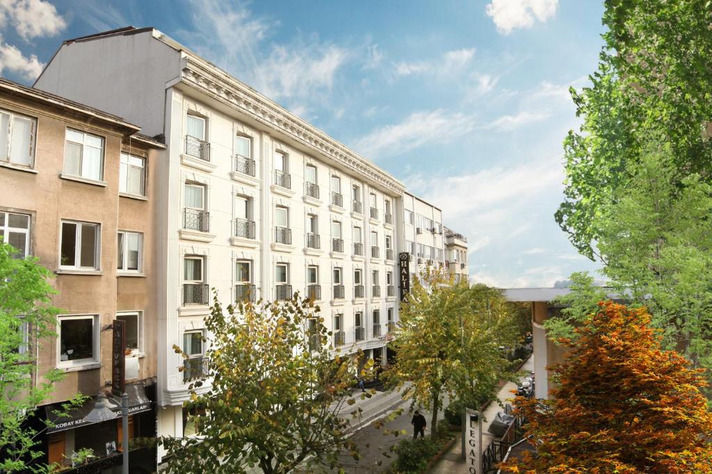 een groot wit gebouw met bomen ervoor bij Halifaks Hotel in Istanbul