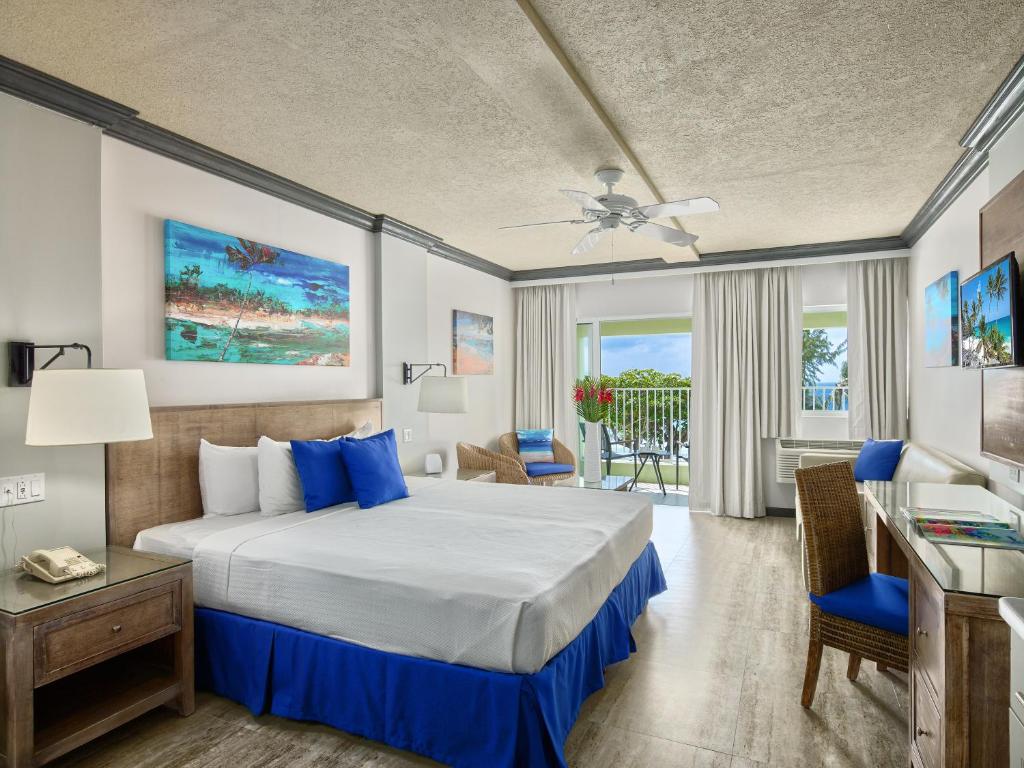 a hotel room with a bed and a desk and a window at Coconut Court Beach Hotel in Bridgetown