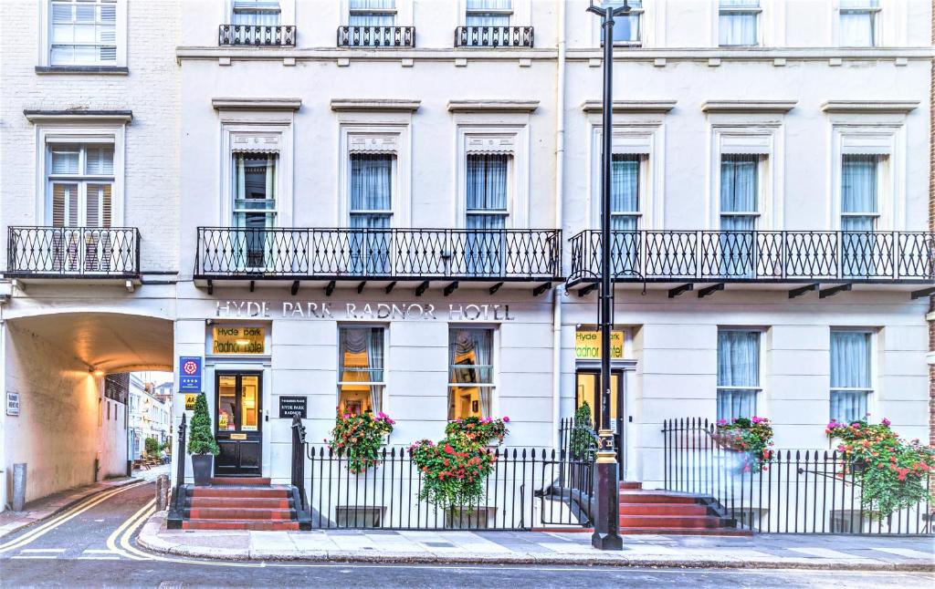 a white building with flowers in front of it at Hyde Park Radnor Hotel B&B in London