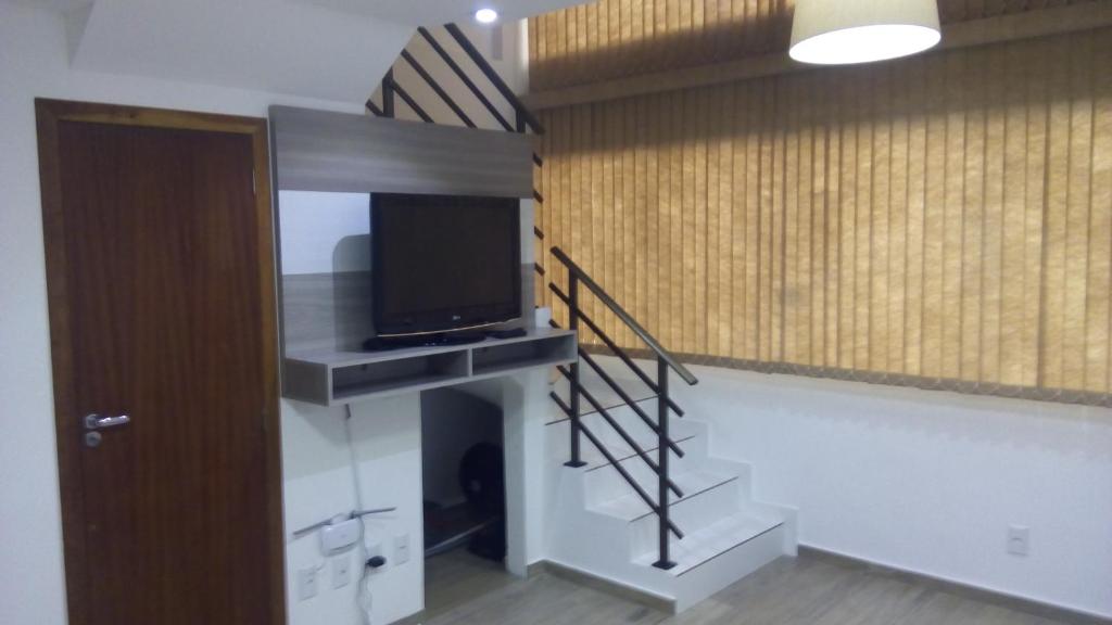 a room with a staircase with a flat screen tv at Loft torres Las piedras praia da Cal in Torres