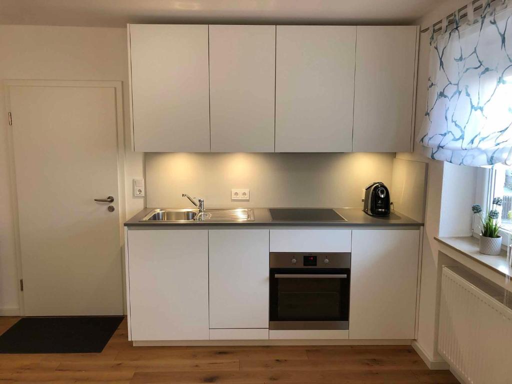 a kitchen with white cabinets and a sink at Ferber 28 in Monheim