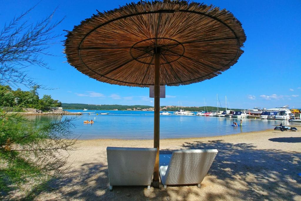 einen Strand mit zwei Stühlen und einem Sonnenschirm auf dem Sand in der Unterkunft Fisherman's glamping village in Klimno