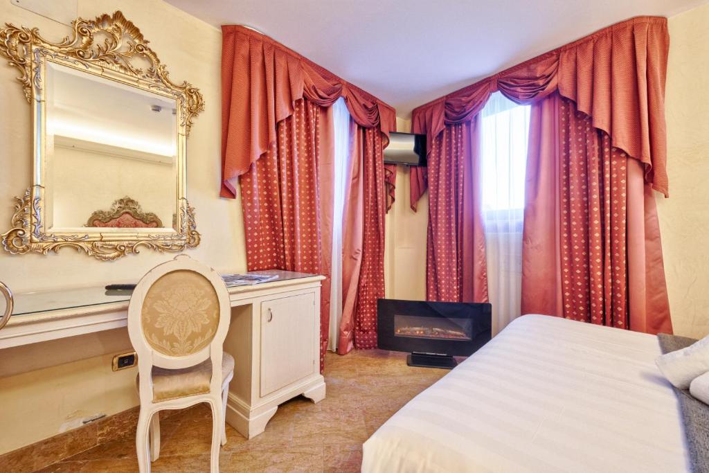 a bedroom with a bed and a mirror and a chair at Hotel Vecellio Venice on the Lagoon in Venice
