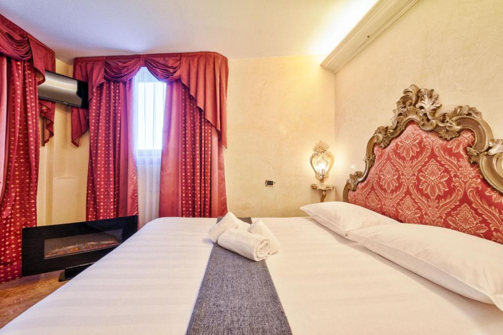 a bedroom with a large bed with red curtains at Hotel Vecellio Venice Lagoon View in Venice