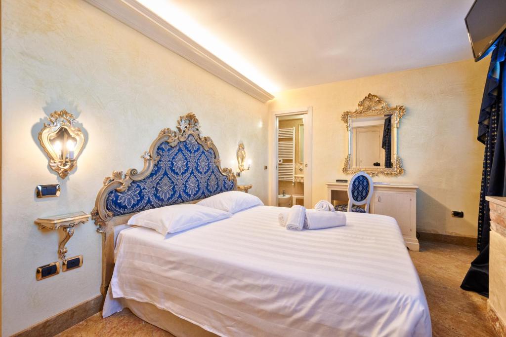 a bedroom with a large white bed with a blue headboard at Hotel Vecellio Venice on the Lagoon in Venice