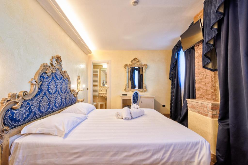 a bedroom with a bed with a blue and white headboard at Hotel Vecellio Venice on the Lagoon in Venice